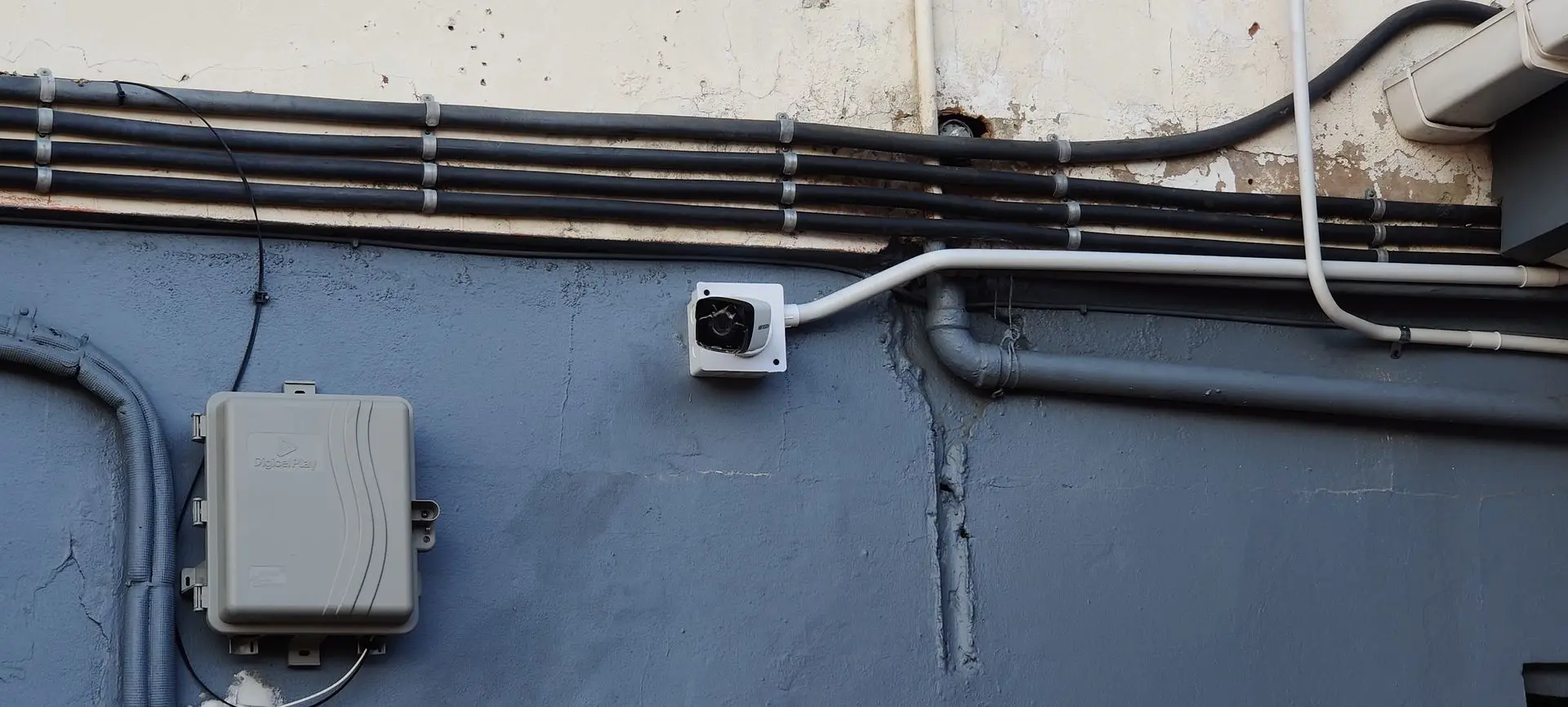 Wall-mounted dome camera on a concrete wall with conduit Commercial dome CCTV camera installation with structured conduit in Trinidad